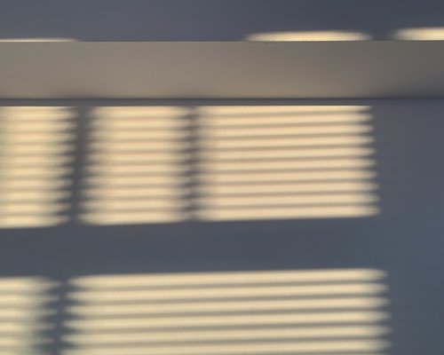 Abstract view of natural sunlight entering a room through partially closed blinds
