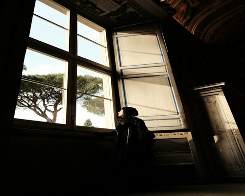 A relaxed person looking thoughtfully out of a large city window